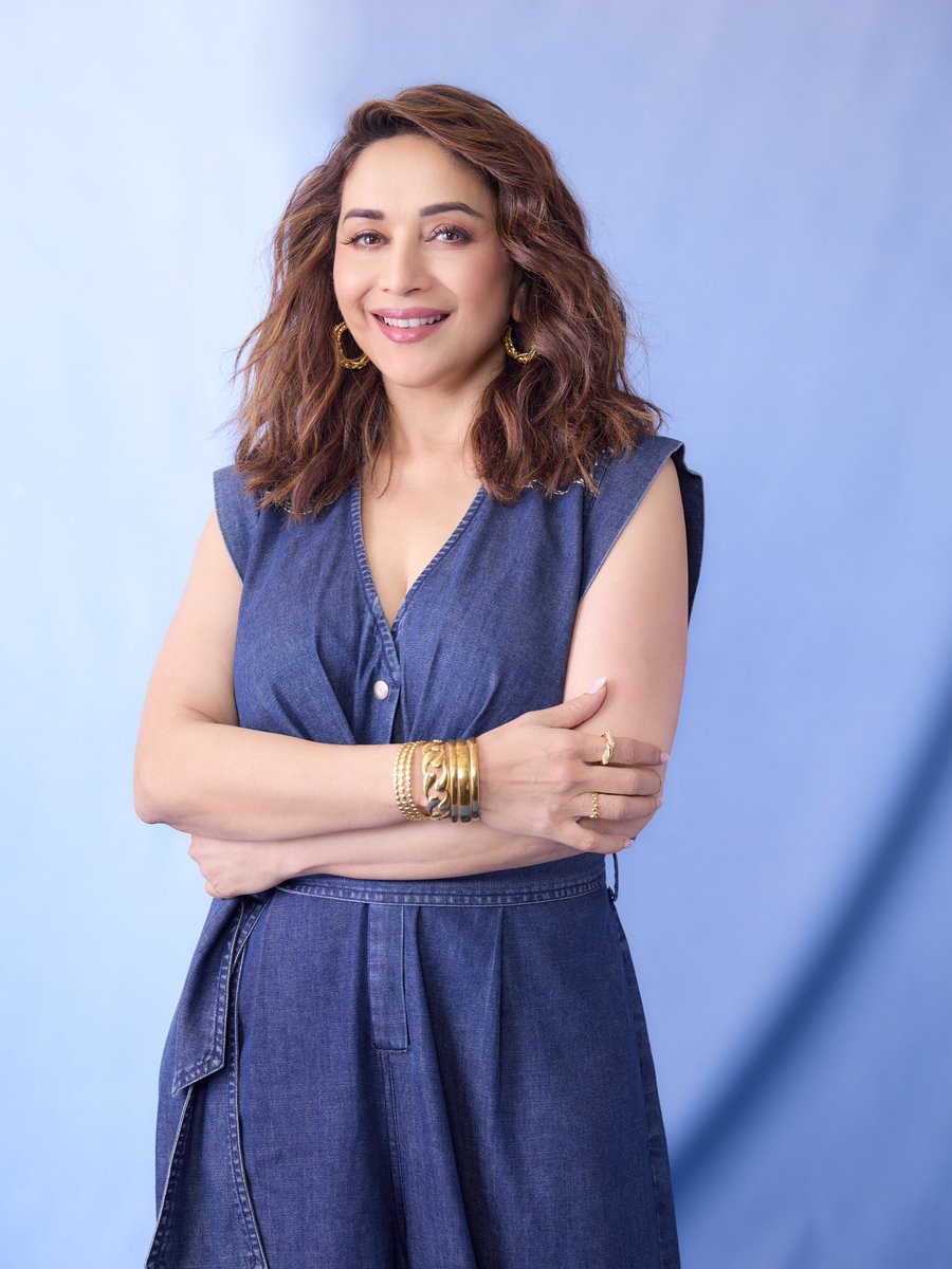 డెనిమ్ అవుట్‌ఫిట్‌లో స్టూడియో బ్యాక్‌డ్రాప్ ముందు నిలబడి ఉన్న మాధురీ దీక్షిత్