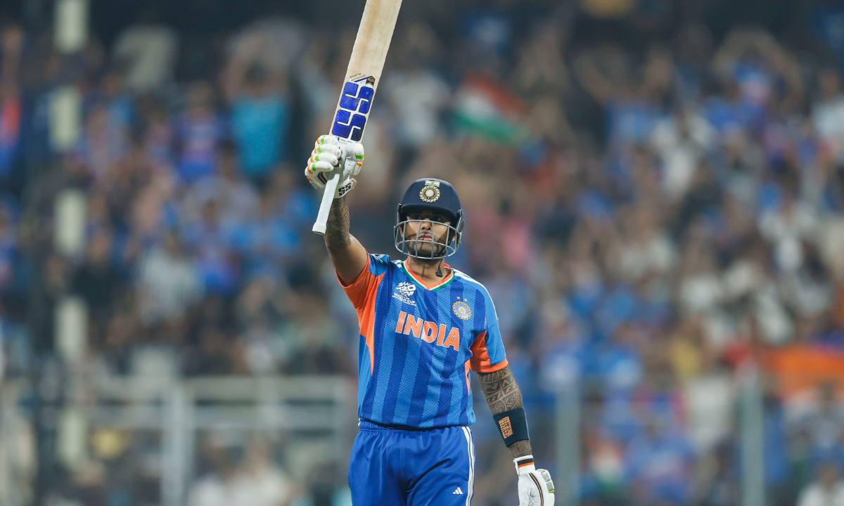Indian cricketer celebrating a scoring milestone by raising his bat during a T20 World Cup match in a crowded stadium