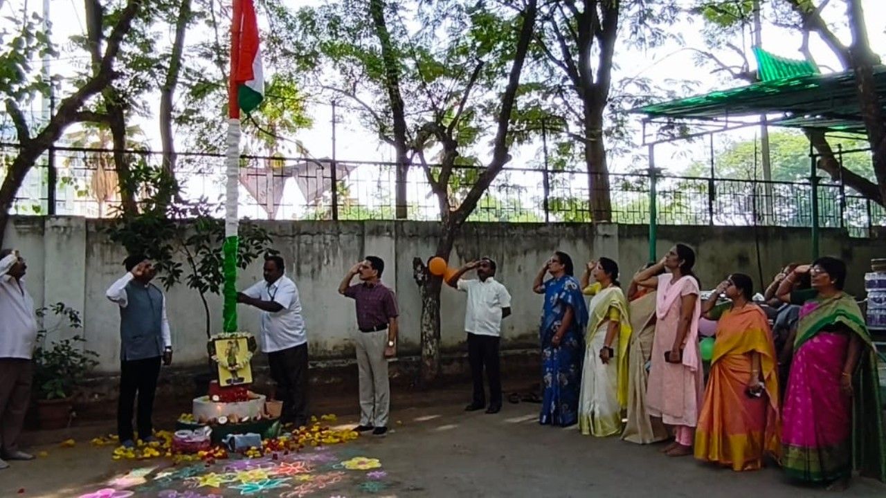 Officials and staff members standing in salute during the Indian National Flag hoisting ceremony as part of Telangana Formation Day 2026 celebrations on a government office campus.